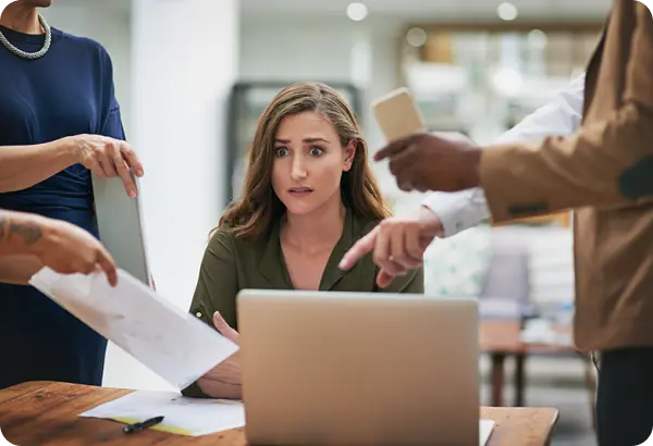 Worried young professional surrounded by people with documents